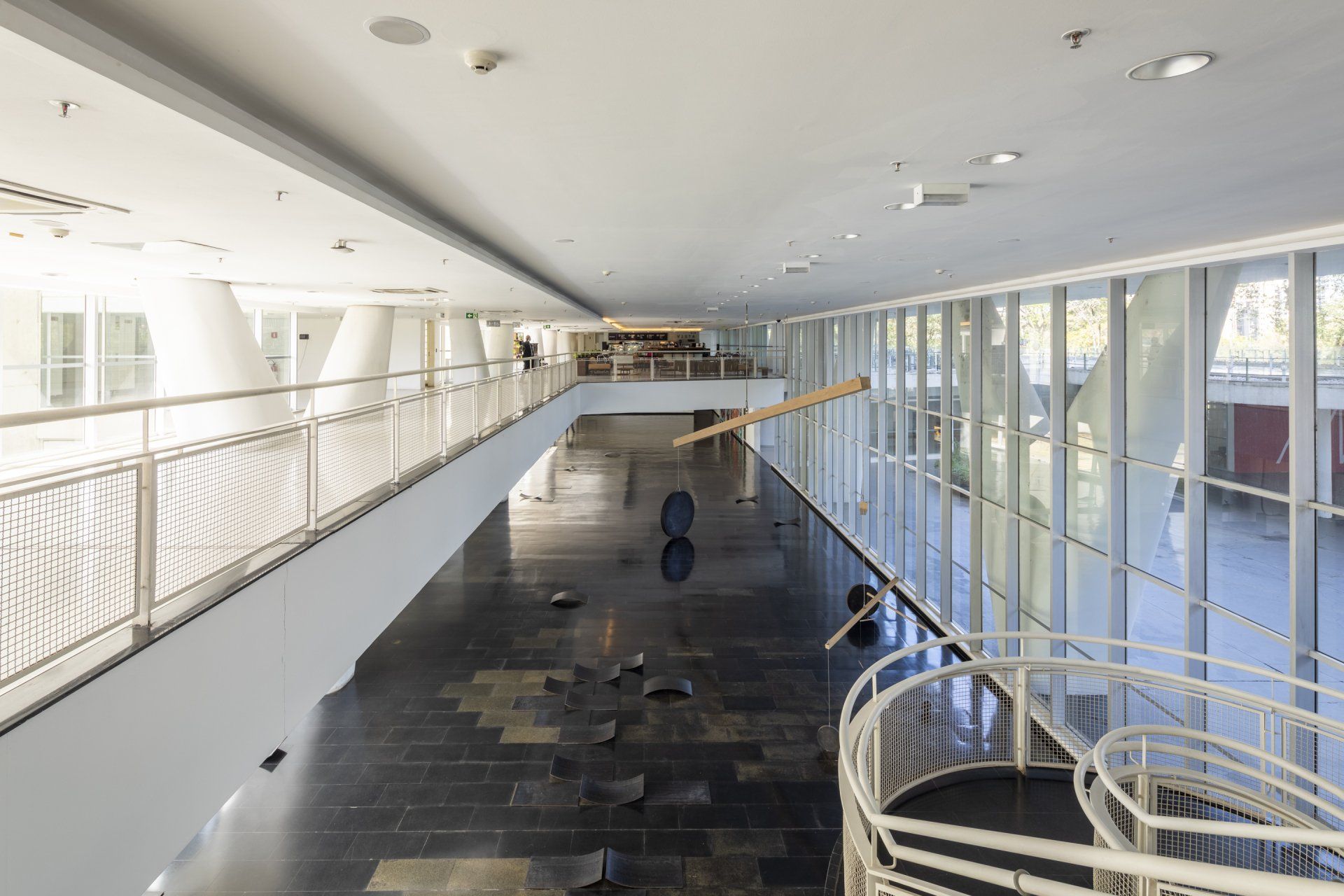 Um longo corredor com uma escada e uma ponte em um prédio.