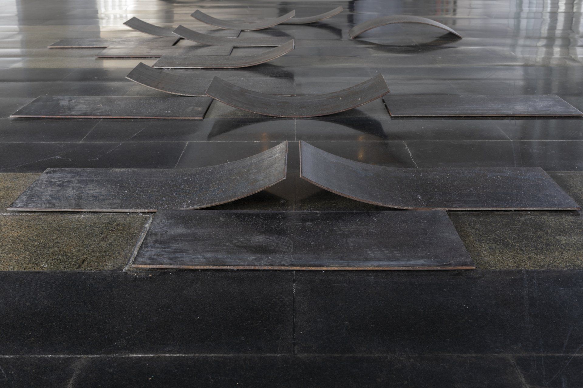 Uma escultura está sobre um chão de azulejos pretos.