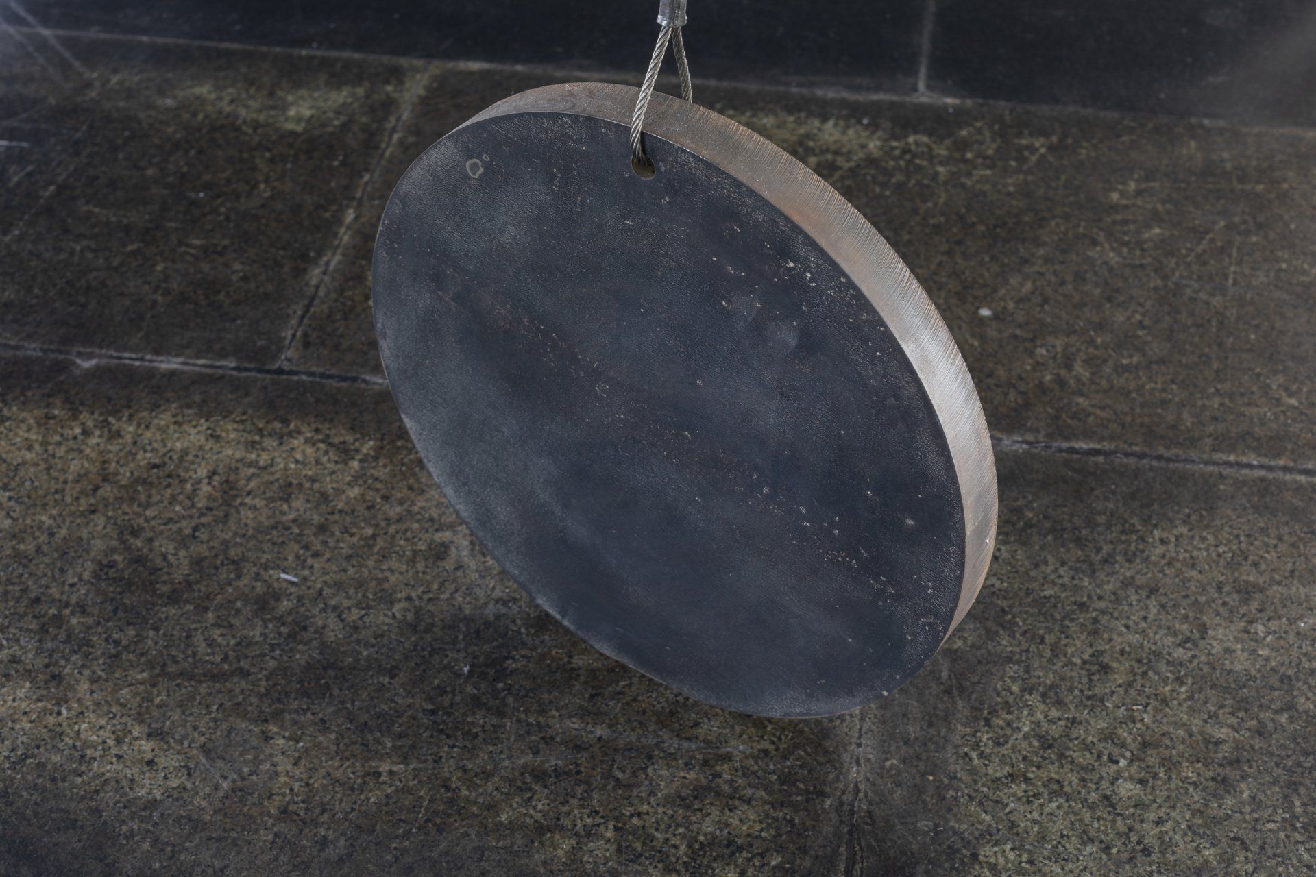 Um círculo preto está pendurado em uma corda no chão.