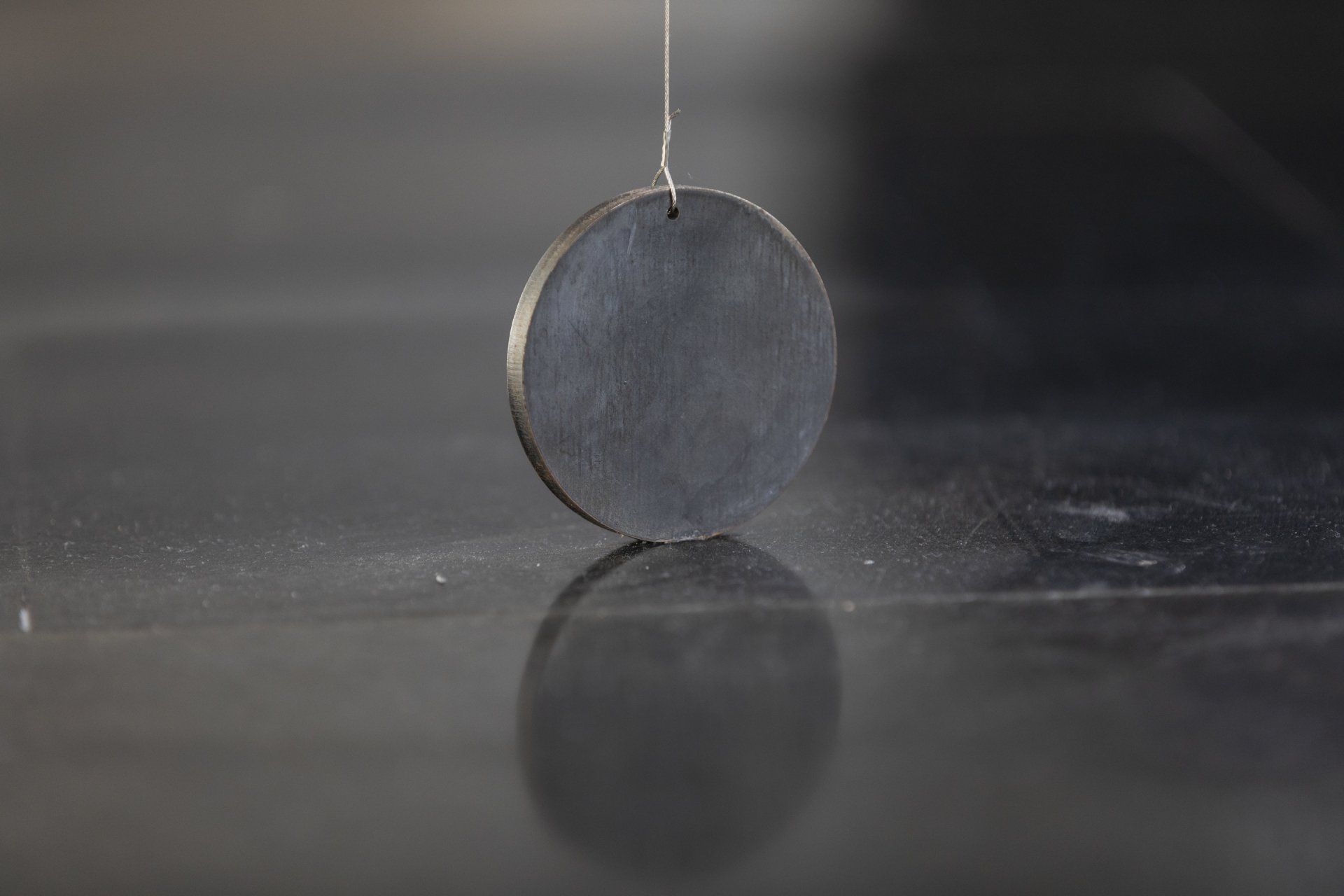 Um círculo de metal está pendurado em uma corda em uma mesa.