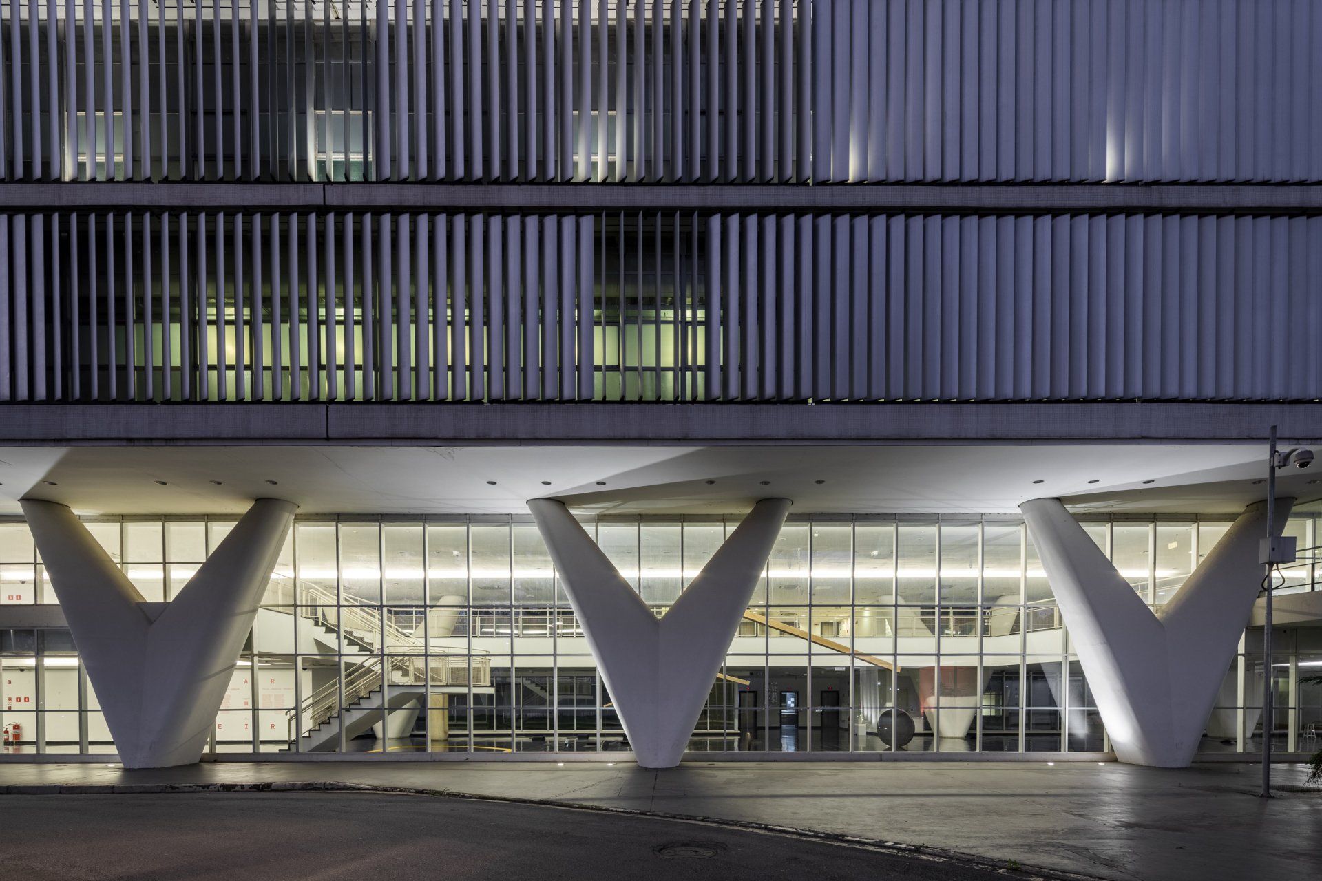 Um grande edifício com muitas janelas fica iluminado à noite.