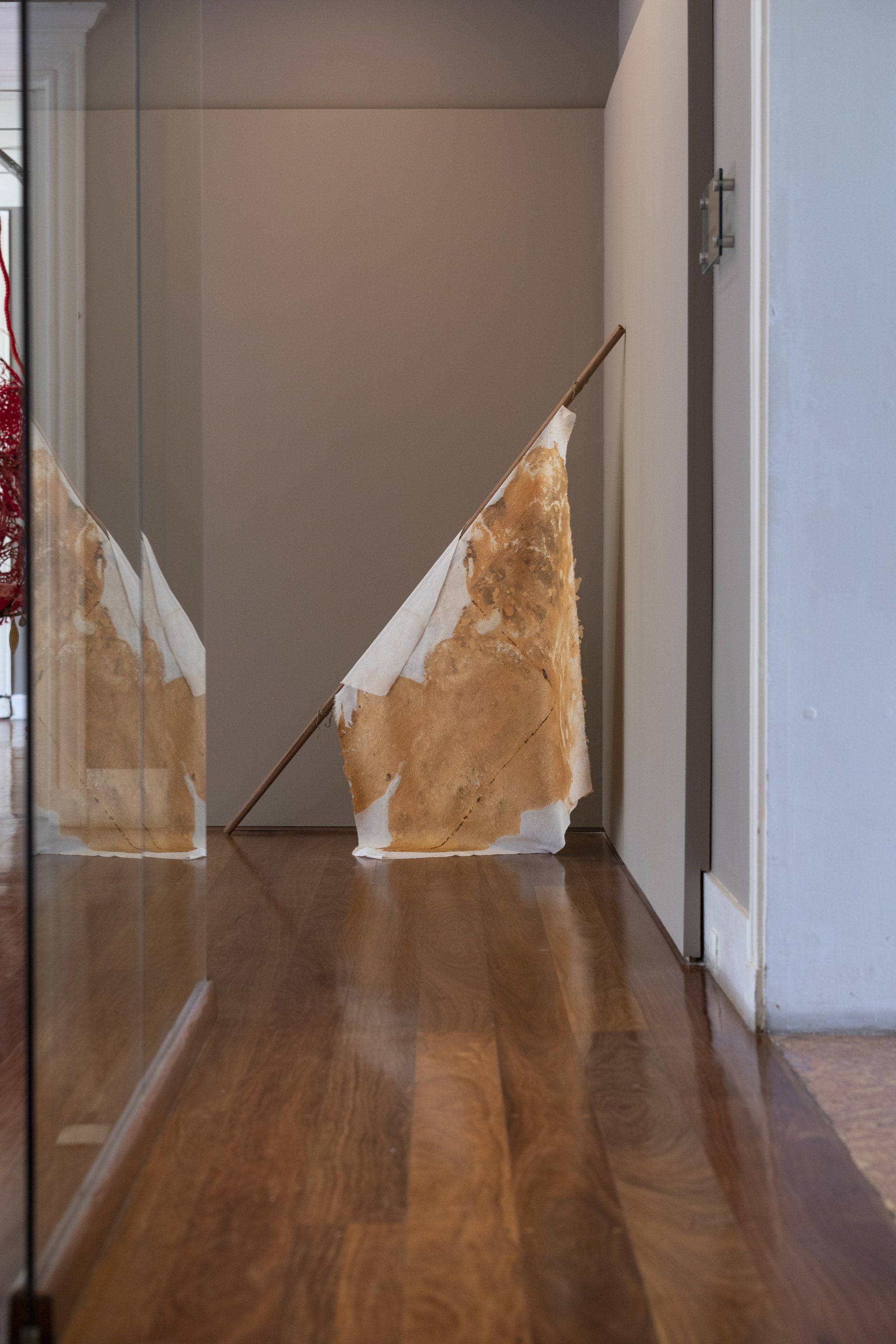 Uma escultura está sobre um piso de madeira em um corredor.