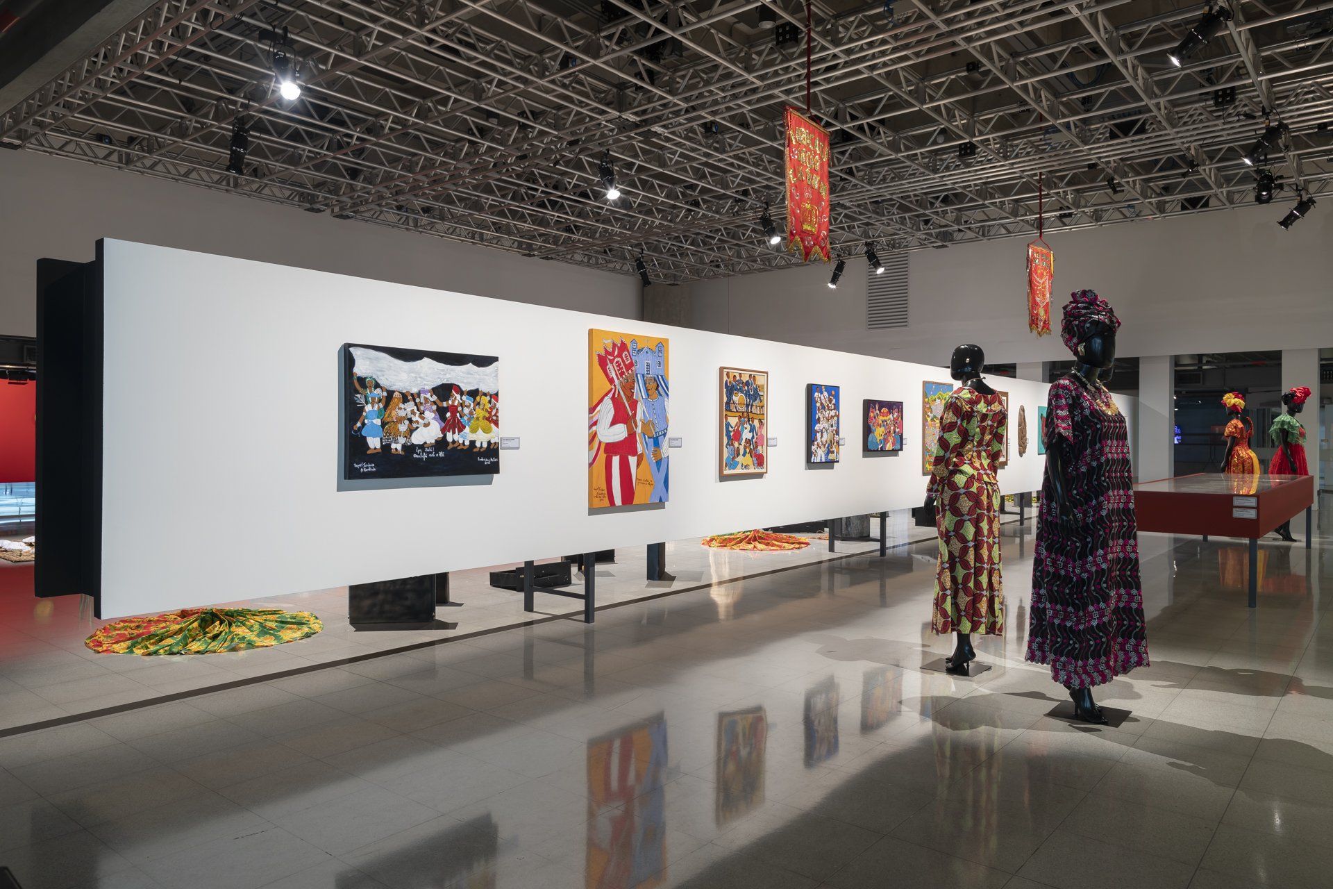 Dois manequins estão diante de uma parede de pinturas em um museu.