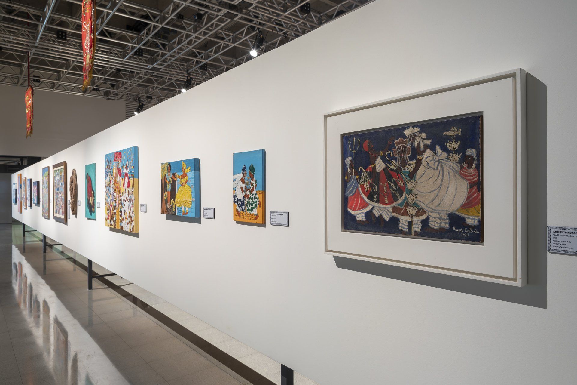 Uma fileira de pinturas está pendurada na parede de um museu.