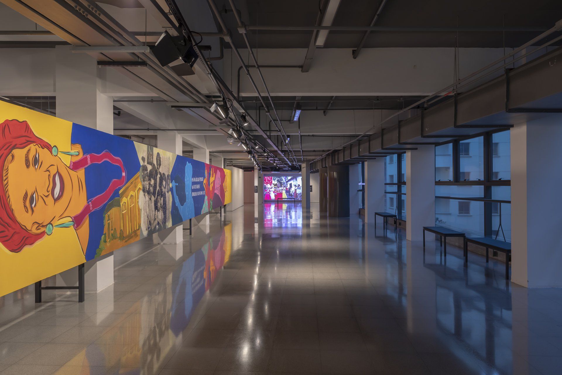 Um longo corredor com muitas pinturas nas paredes.