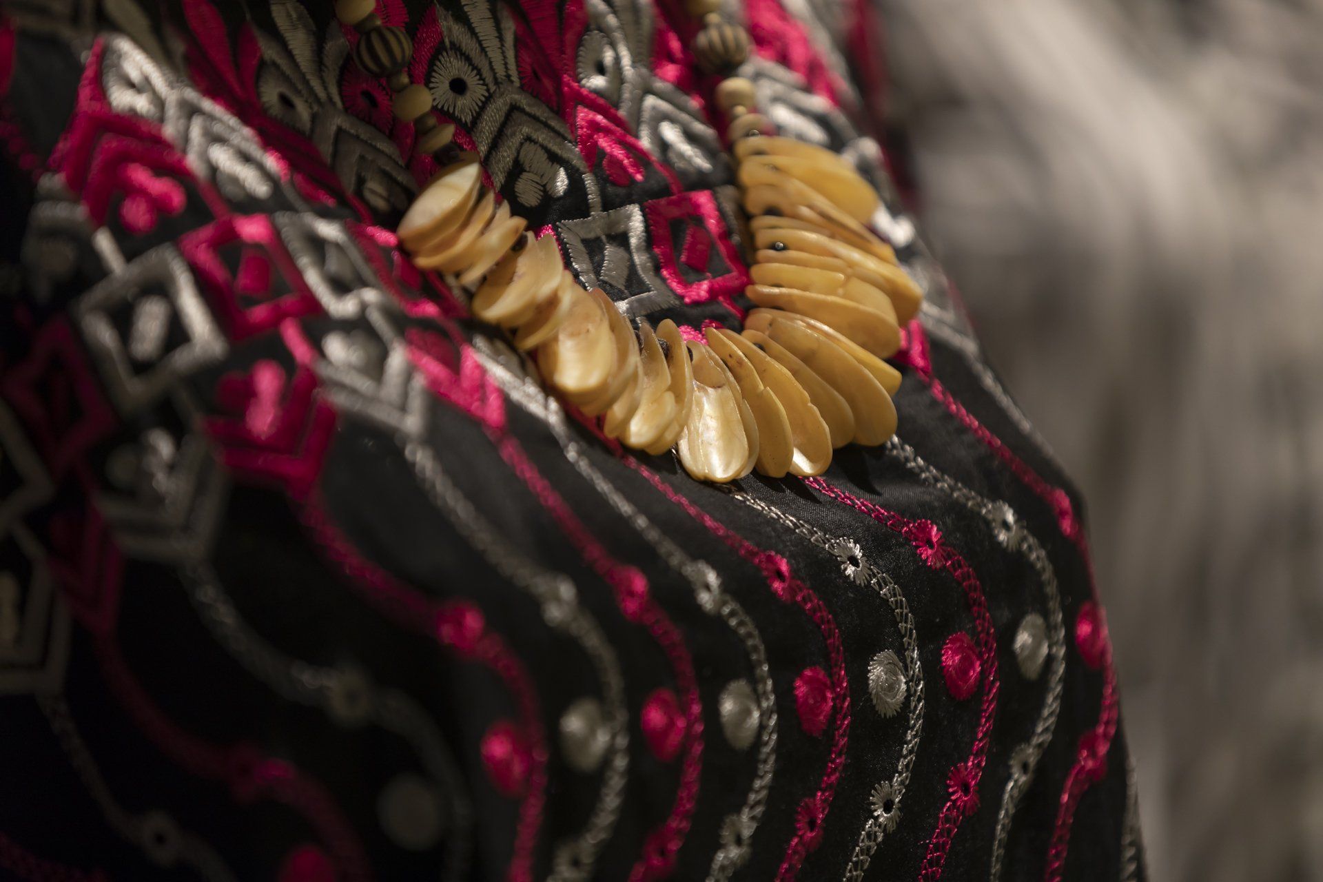 Um close de um colar no ombro de uma mulher.