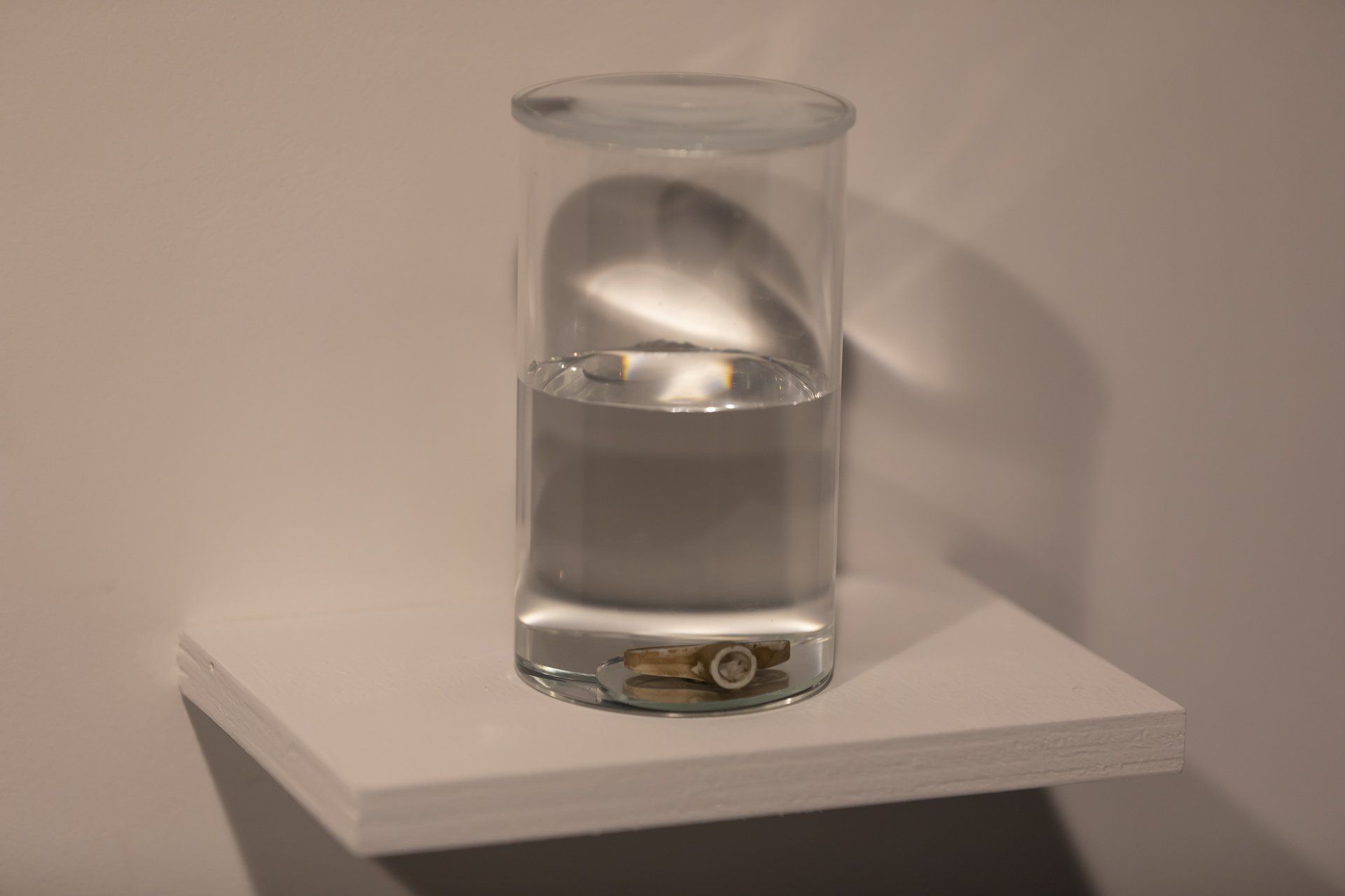 Um copo de água está em uma prateleira branca.