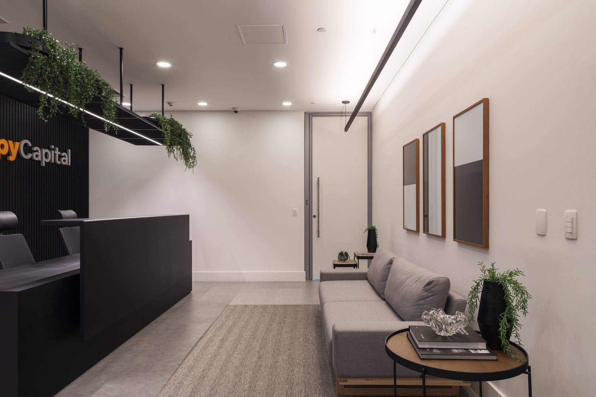 Uma sala de espera com sofá e mesa em frente a um balcão de recepção.