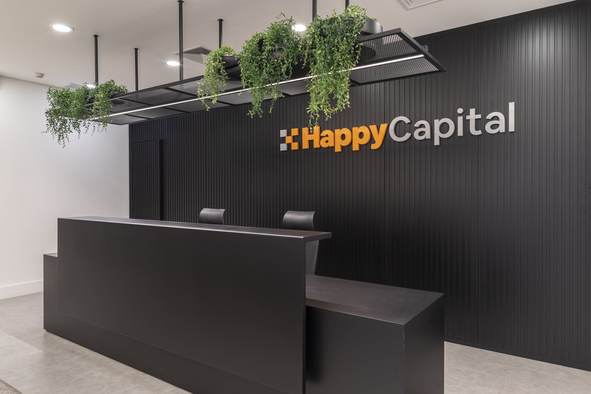Uma área de recepção com uma mesa preta e uma placa que diz capital feliz.