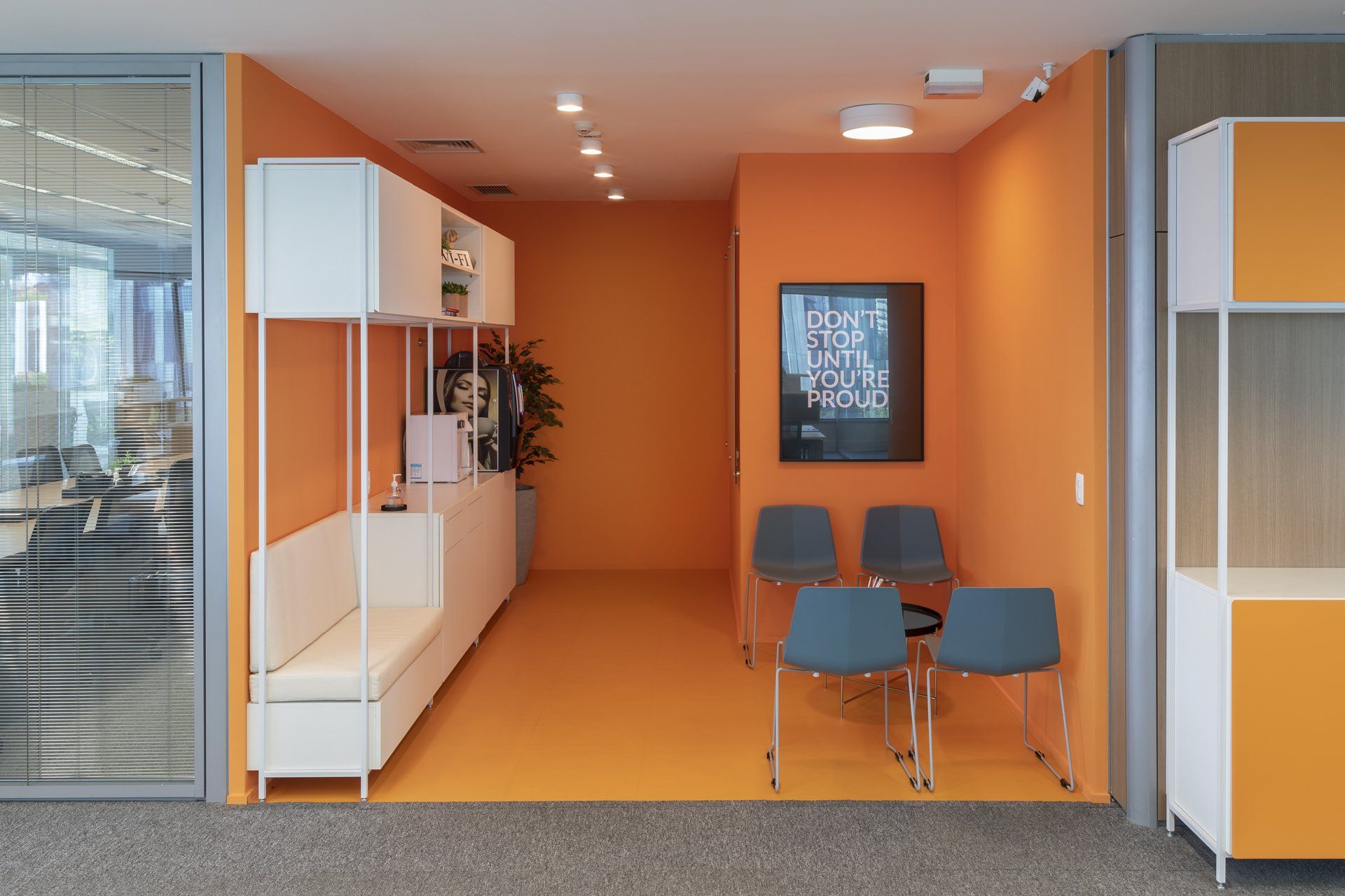 Uma sala de espera com paredes laranja e cadeiras azuis.