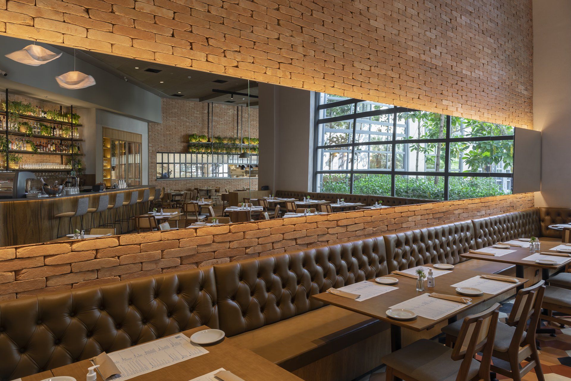 Um restaurante com mesas e cadeiras e uma parede de tijolos.