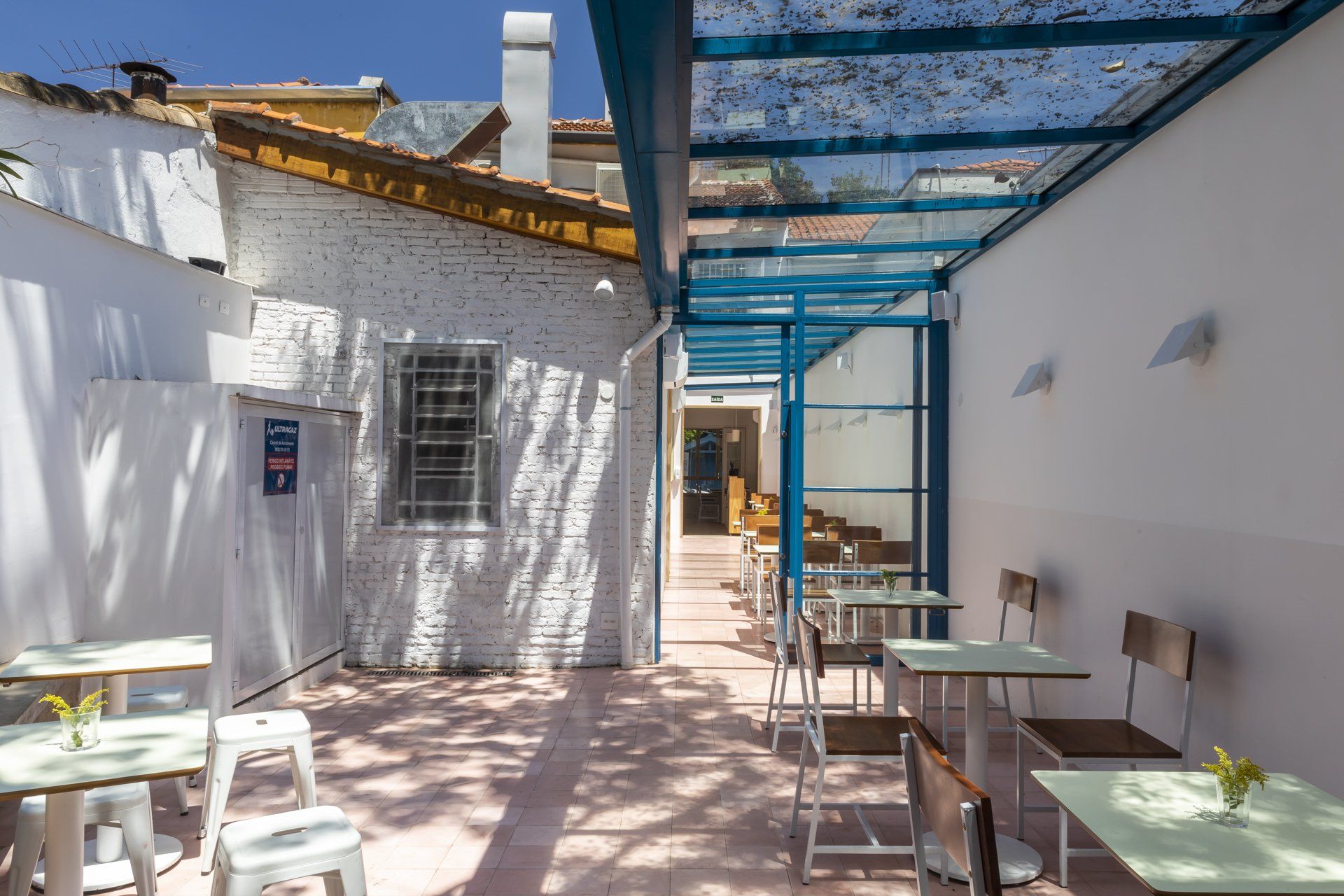 Um restaurante com mesas e cadeiras sob teto de vidro.