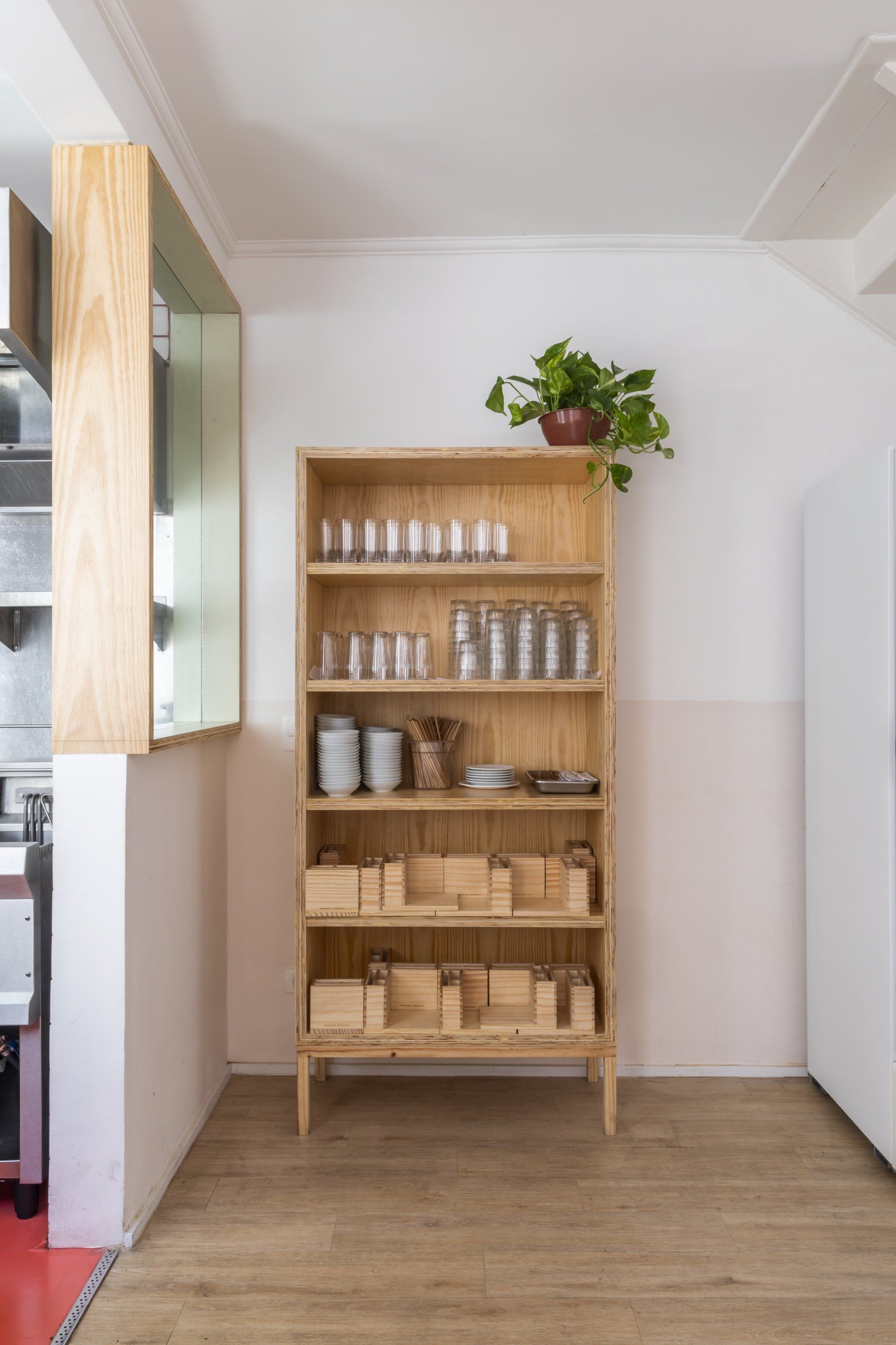 Uma prateleira de madeira com uma planta em cima na cozinha.