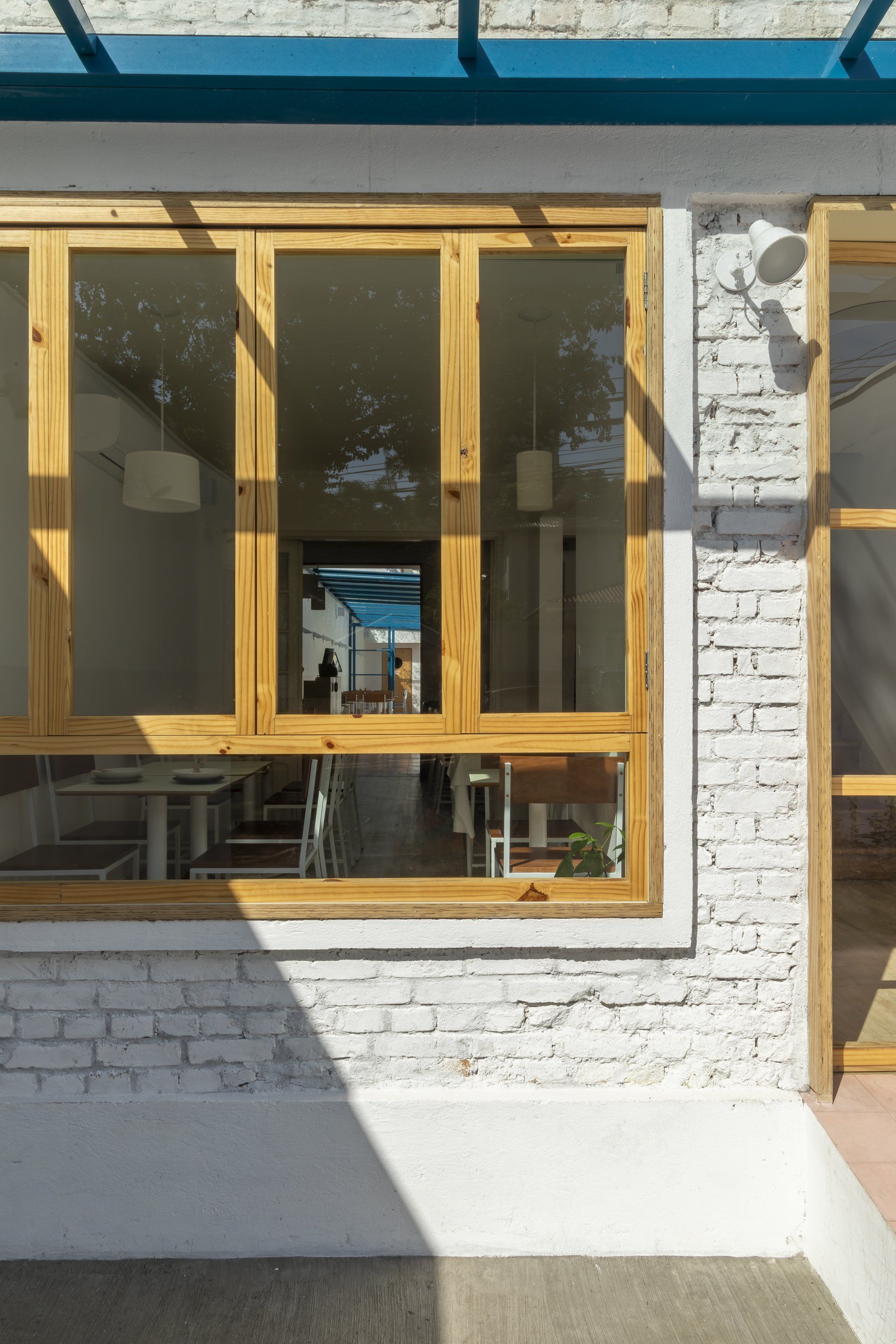 Um prédio de tijolos brancos com janelas de madeira e telhado azul.