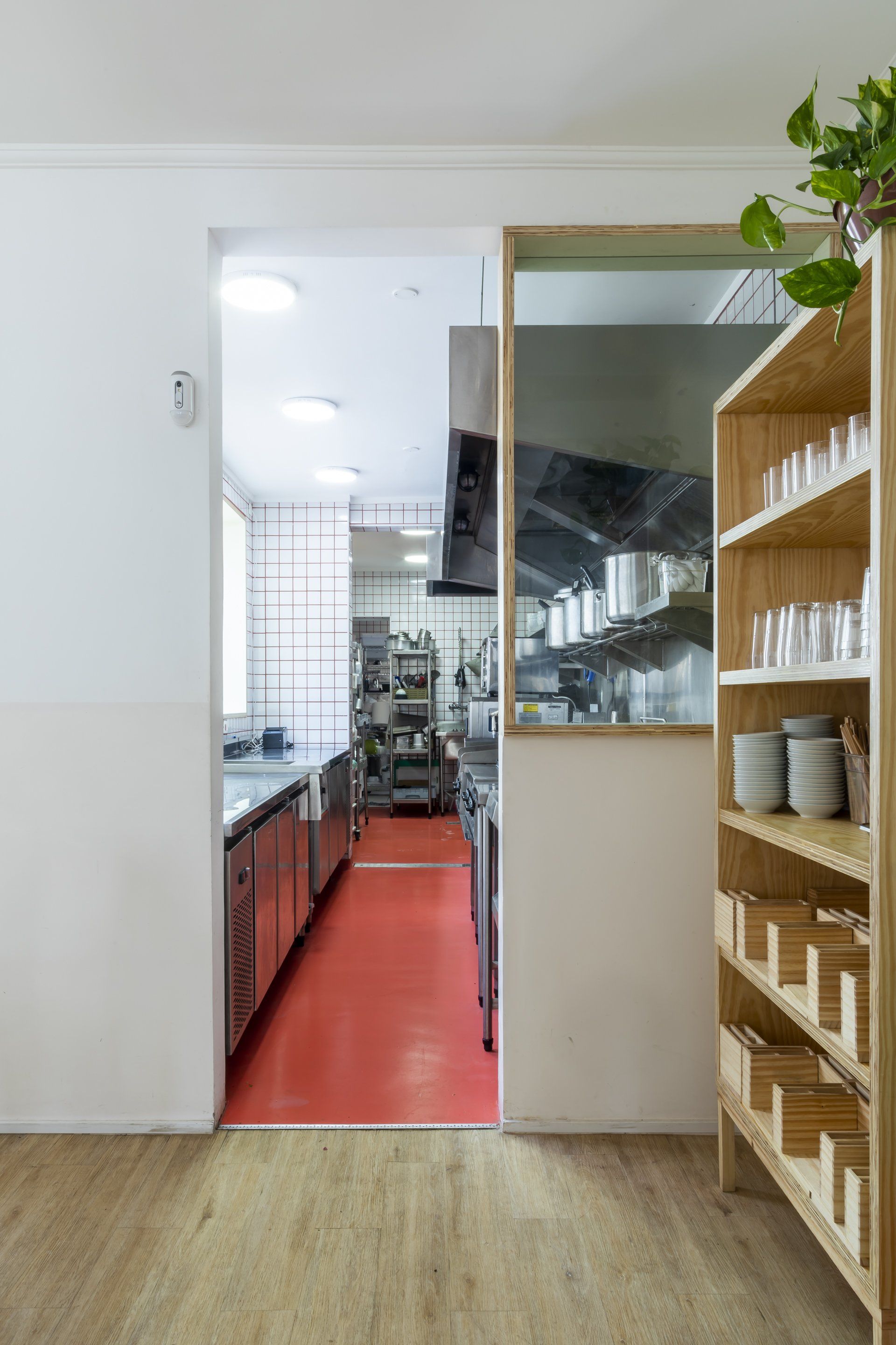 Uma cozinha com piso vermelho e uma prateleira de madeira.