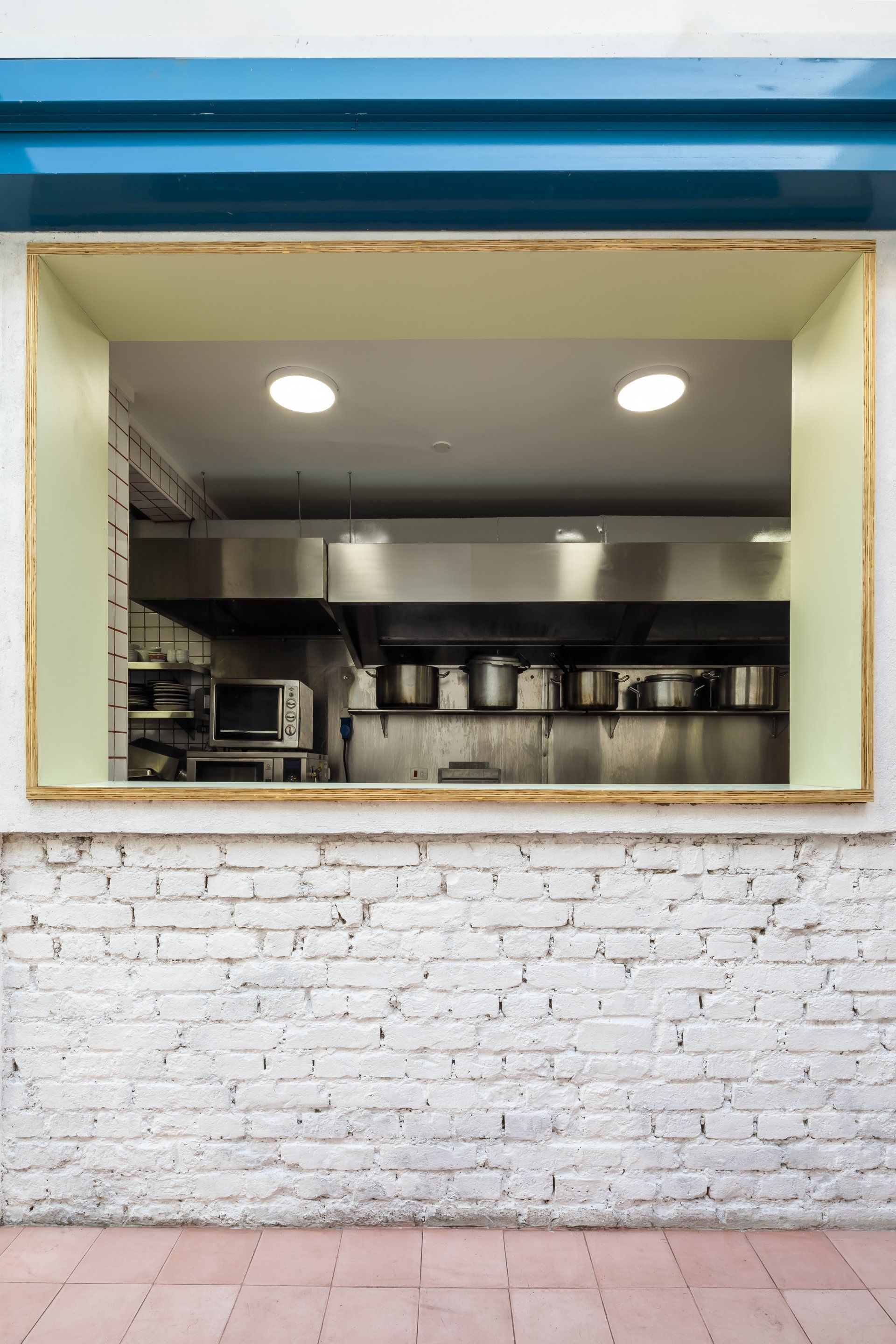 Há uma janela na parede que dá para uma cozinha.