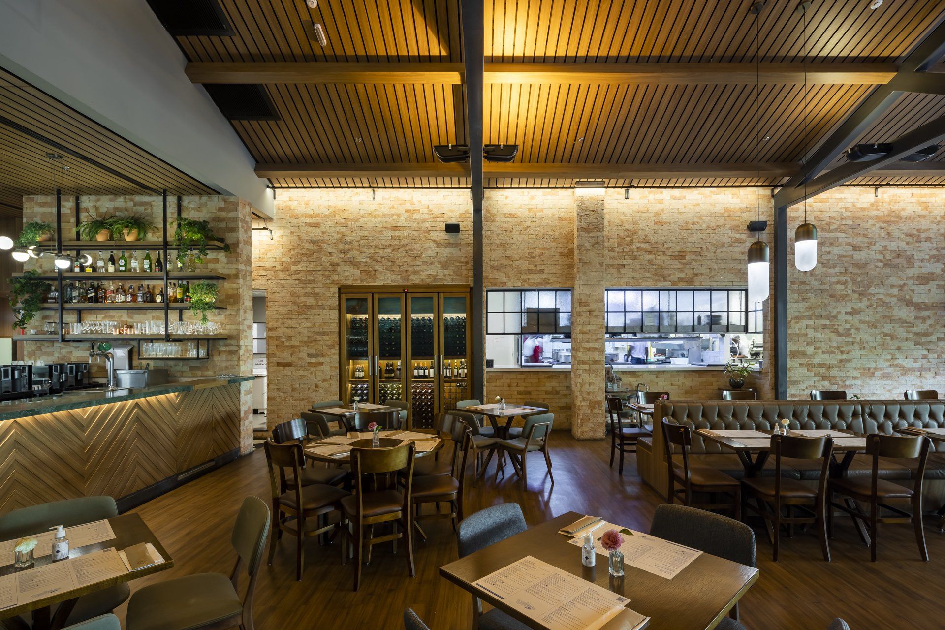 Um restaurante com mesas e cadeiras e uma cozinha ao fundo.