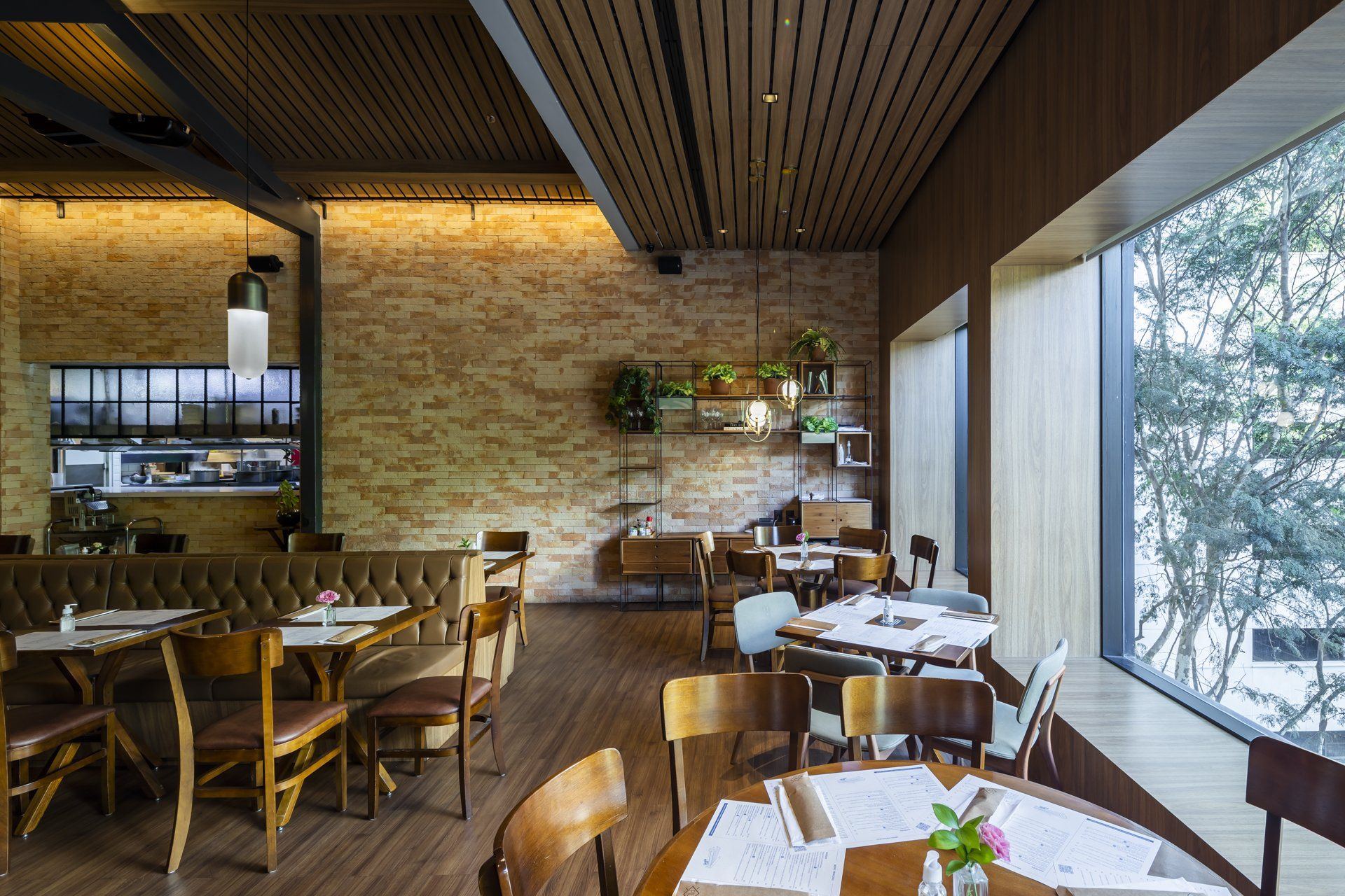 Um restaurante com mesas e cadeiras e uma grande janela.