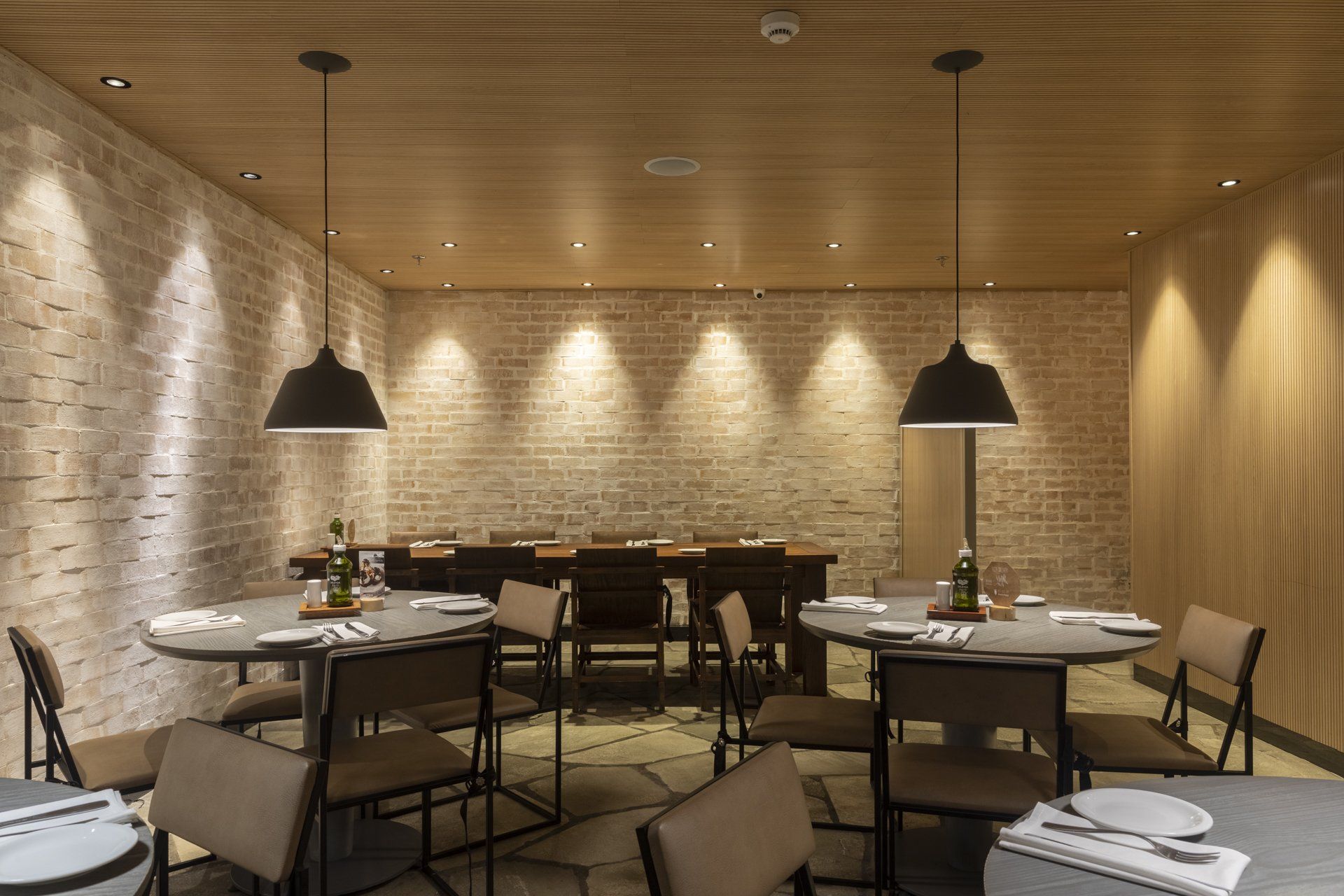 Um restaurante com mesas e cadeiras e uma parede de tijolos.