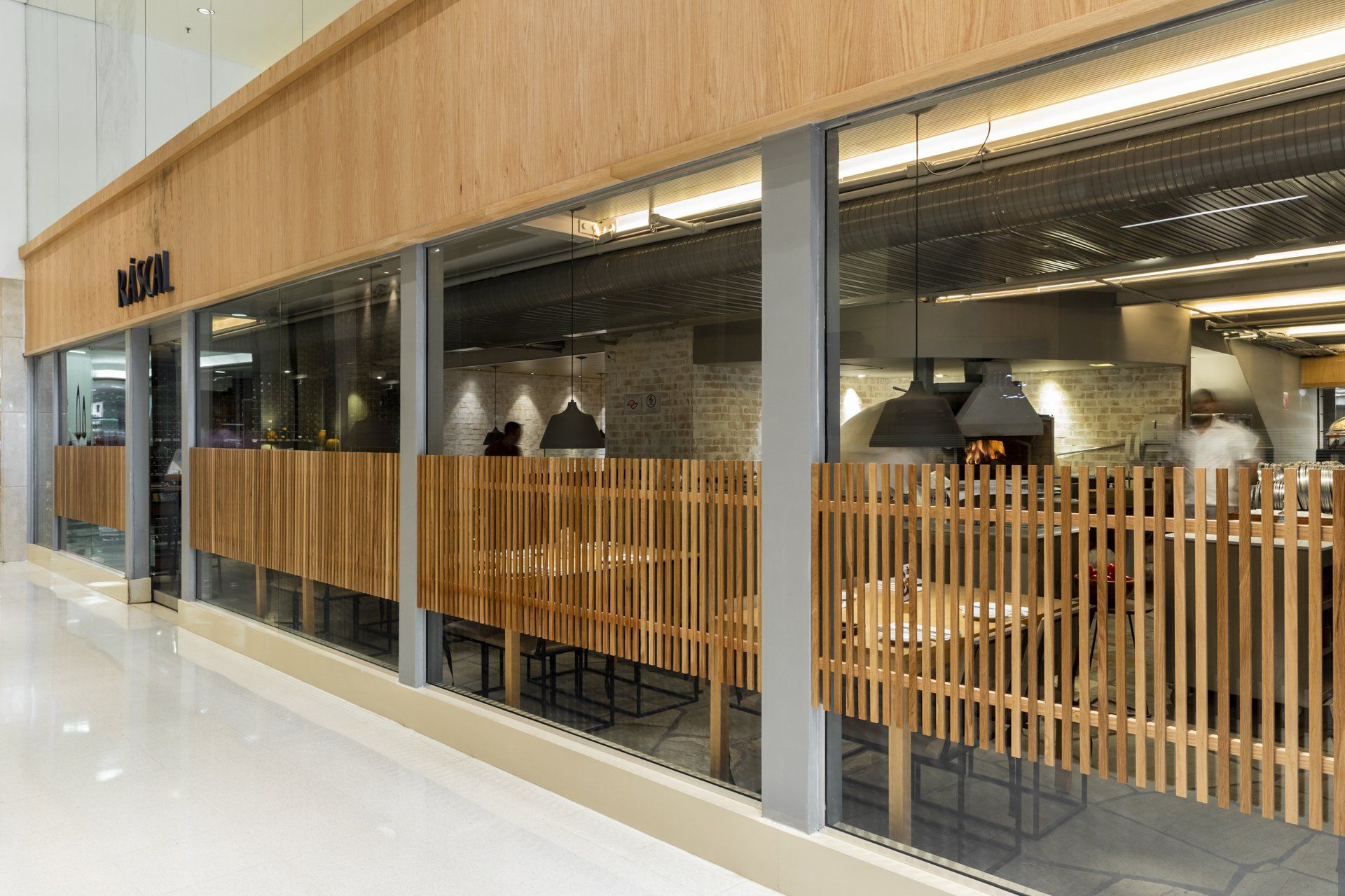 Um restaurante com mesas e cadeiras e uma cerca de madeira na frente.