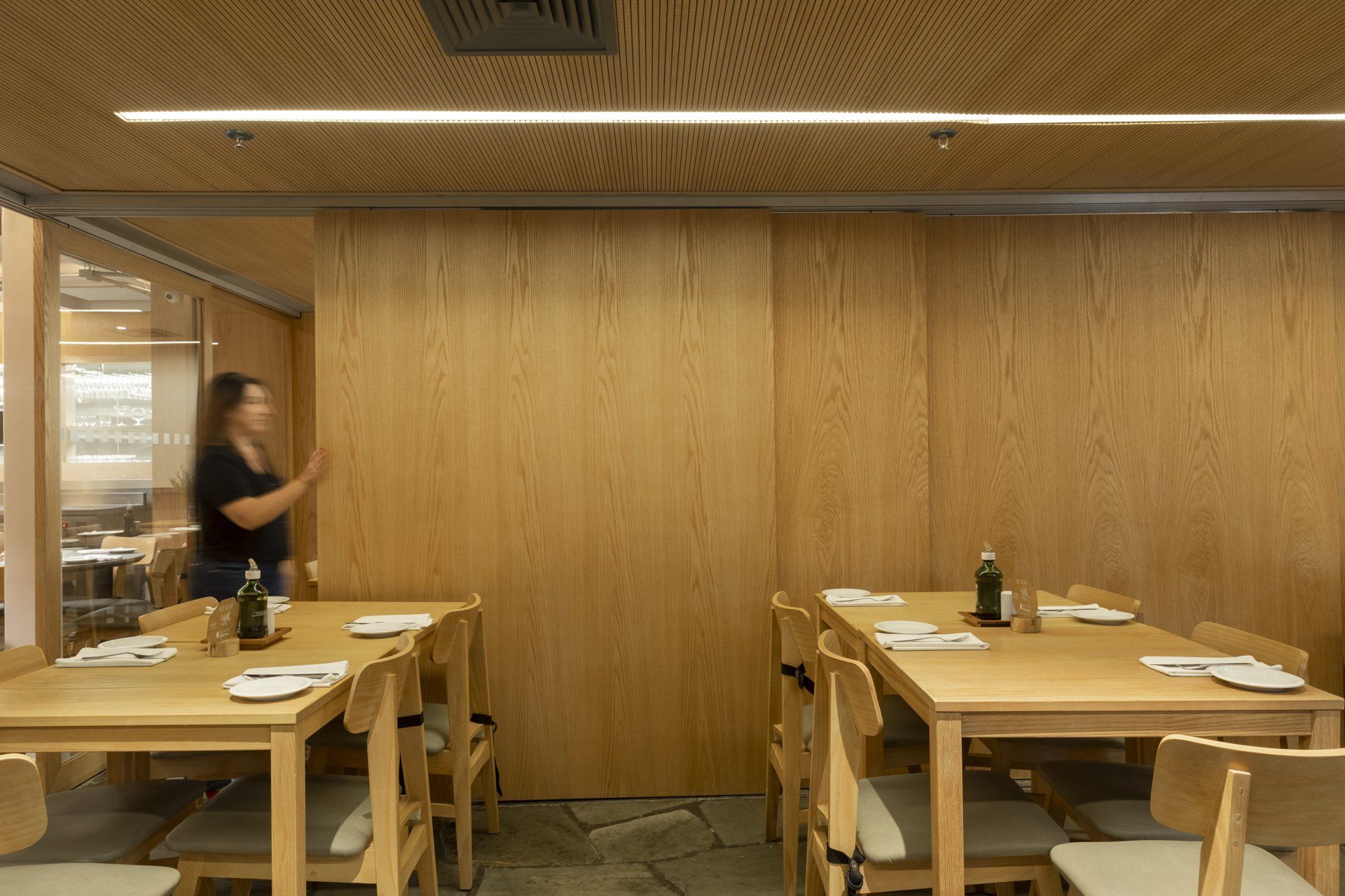 Uma mulher está parada em frente a uma parede de madeira em um restaurante.