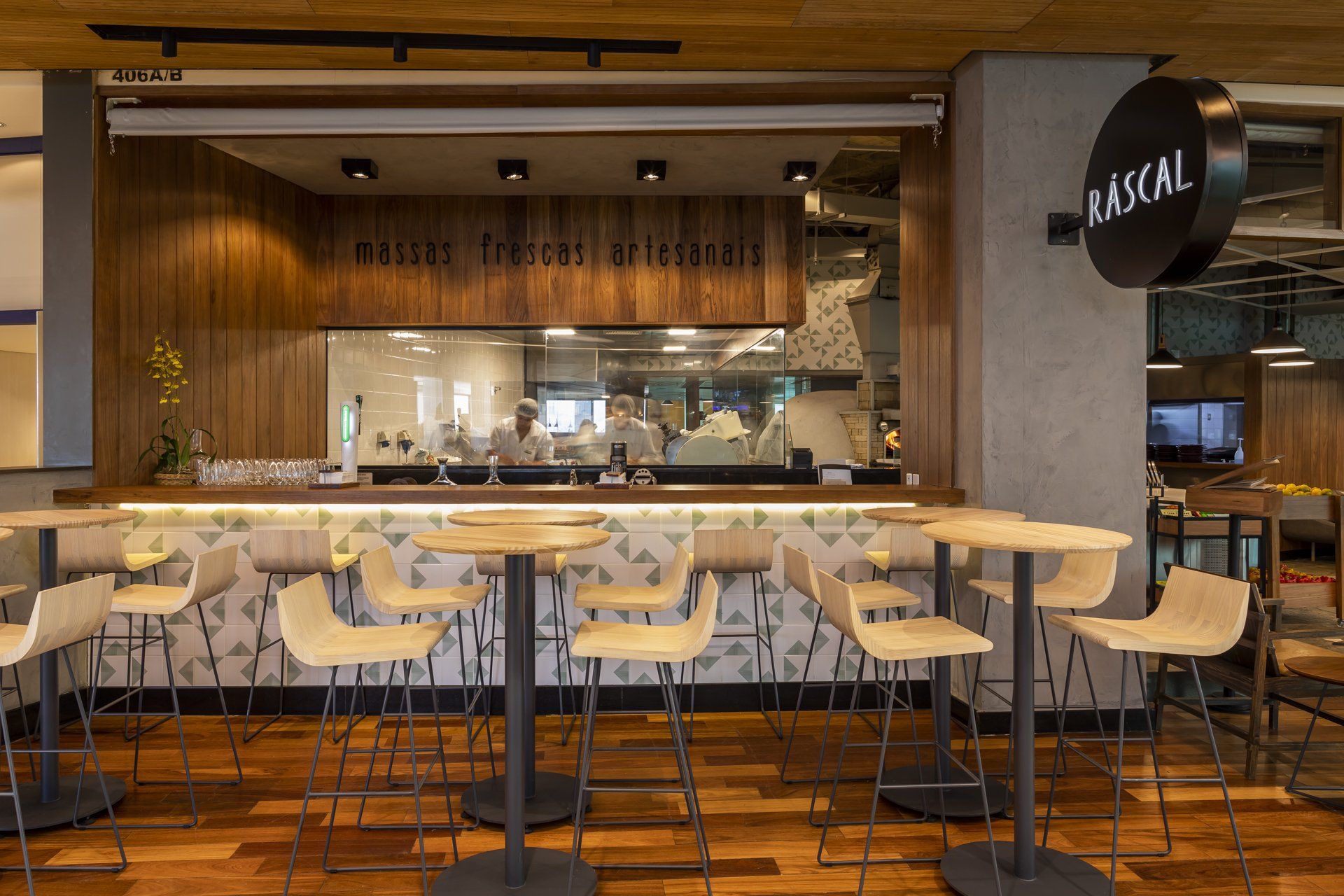 Um restaurante com mesas e cadeiras em frente a um balcão.