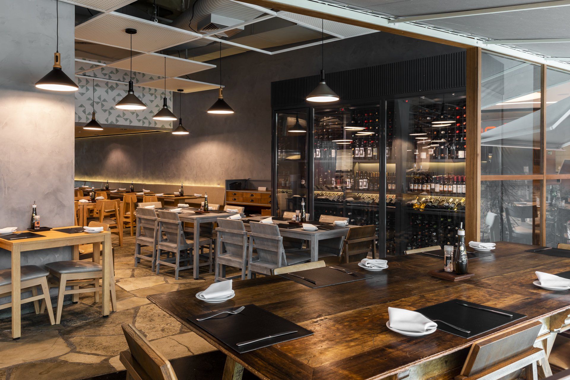 Um restaurante com mesas e cadeiras e uma adega.