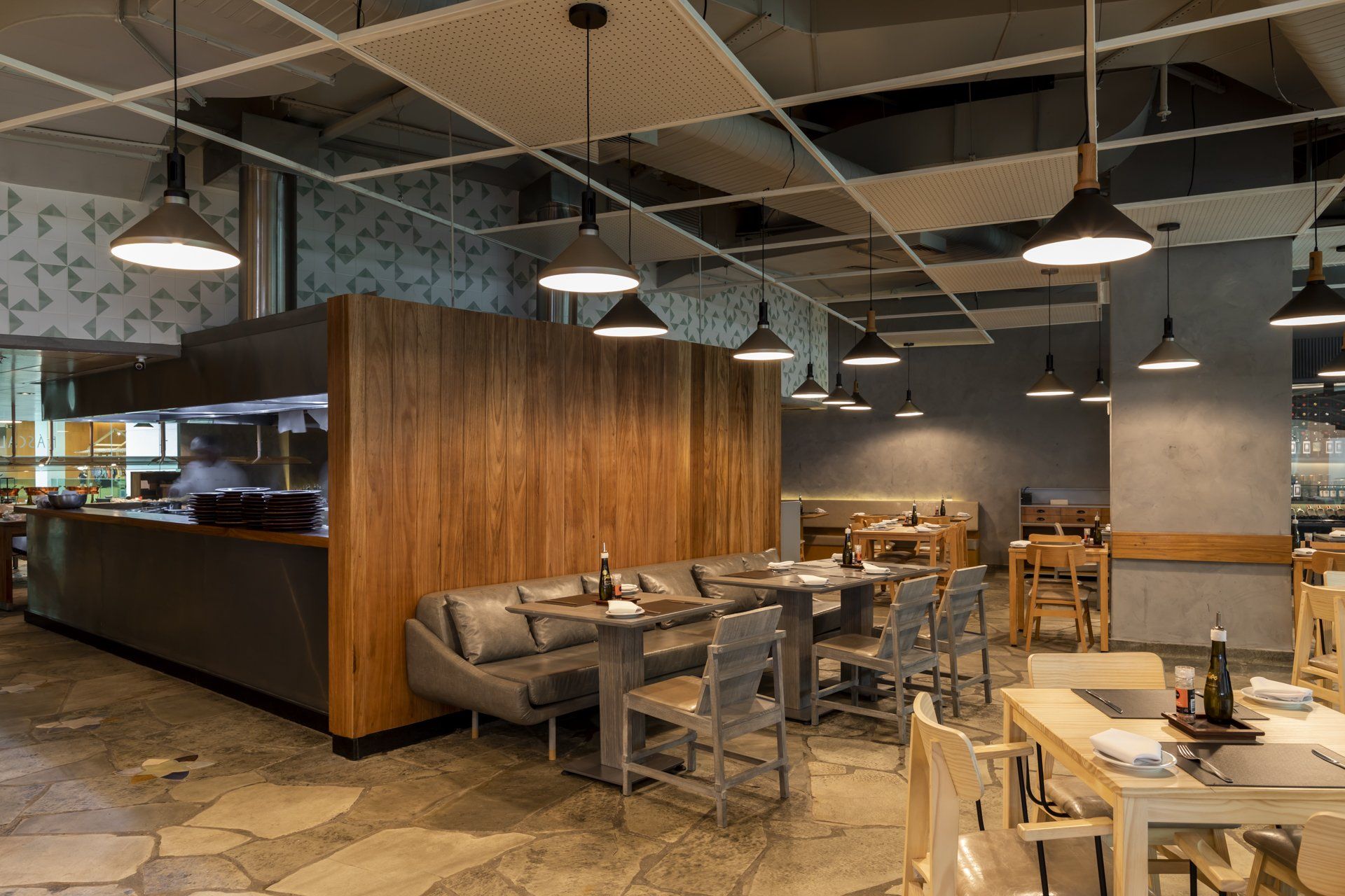 Um restaurante com mesas e cadeiras e uma cozinha ao fundo.