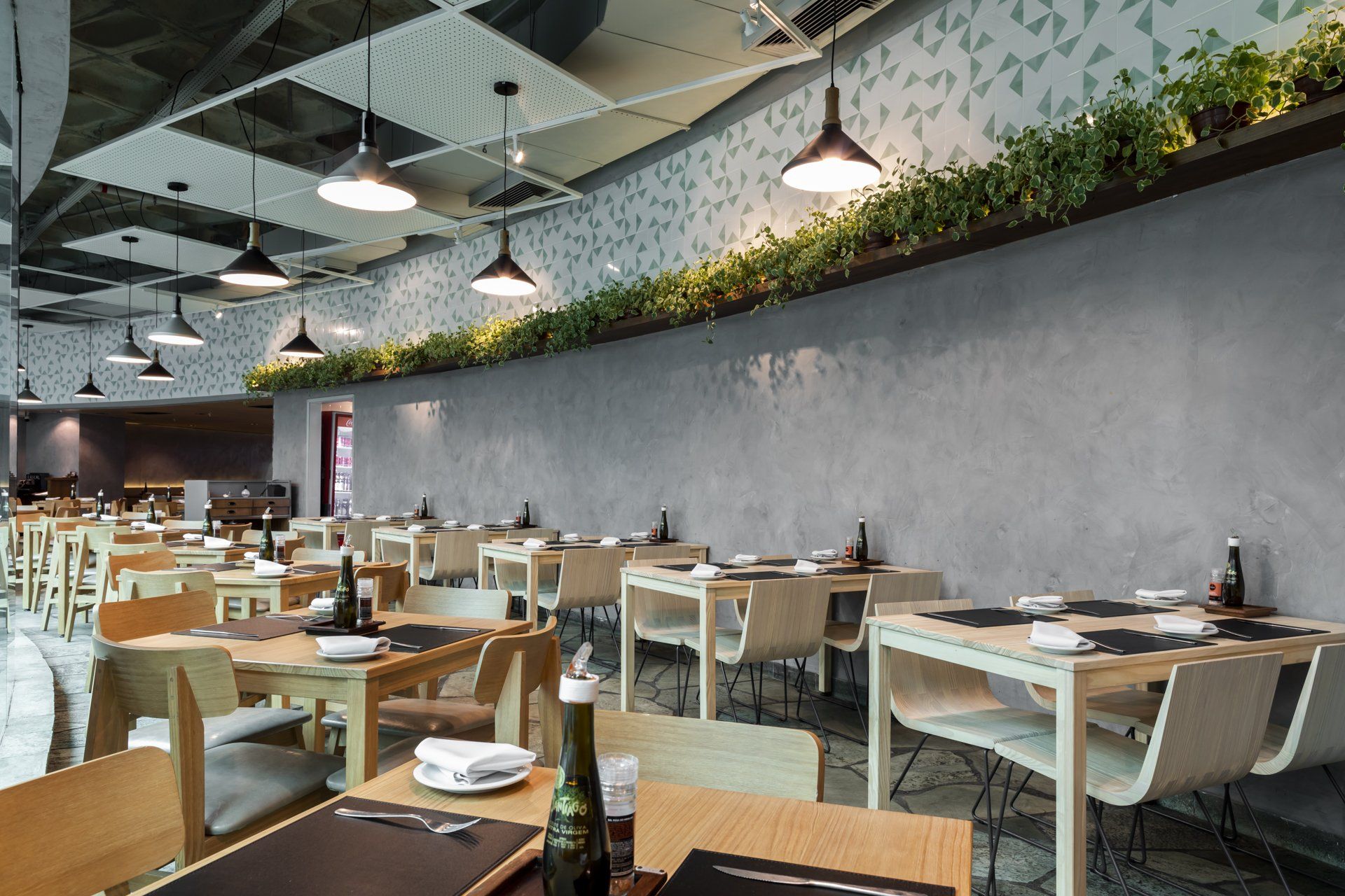 Um restaurante com mesas e cadeiras e uma parede cinza