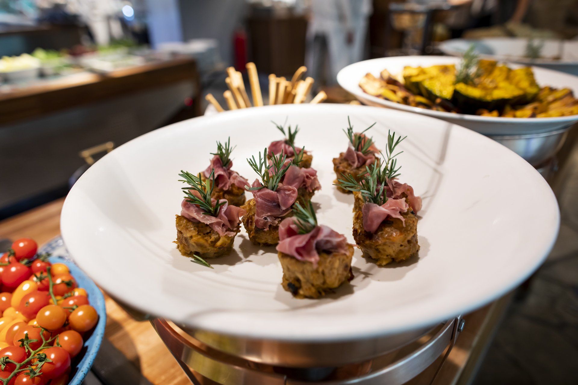 Um prato branco coberto com carne e alecrim sobre uma mesa de madeira.