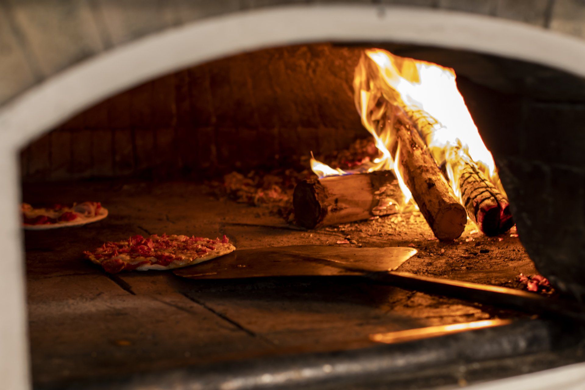 Uma pizza está sendo cozida em forno a lenha.