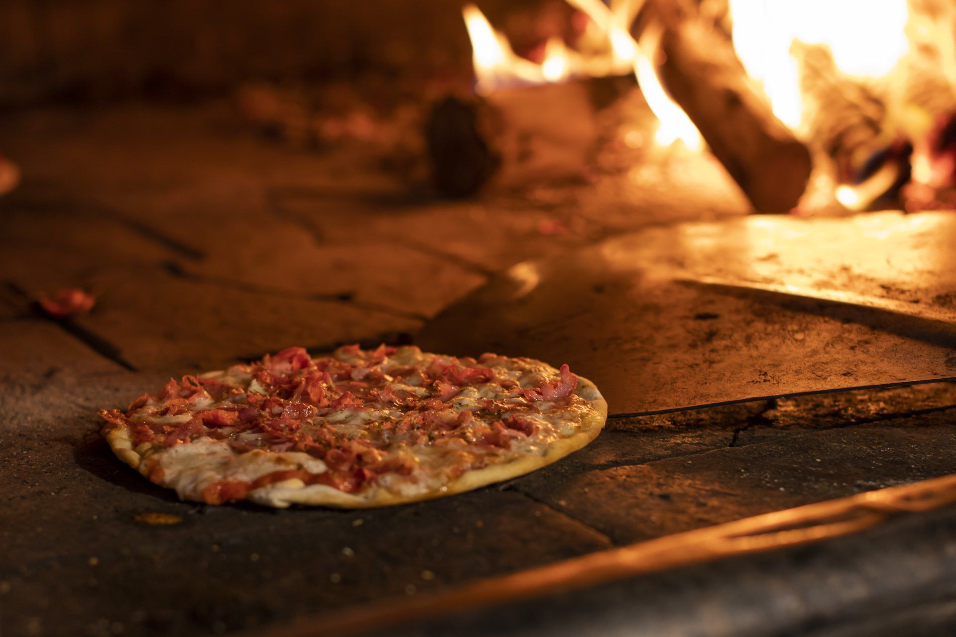 Uma pizza está sendo cozida em forno a lenha.