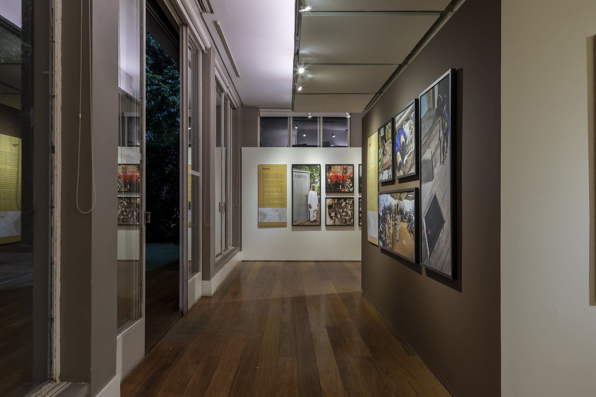 Um longo corredor com pinturas na parede e piso de madeira.