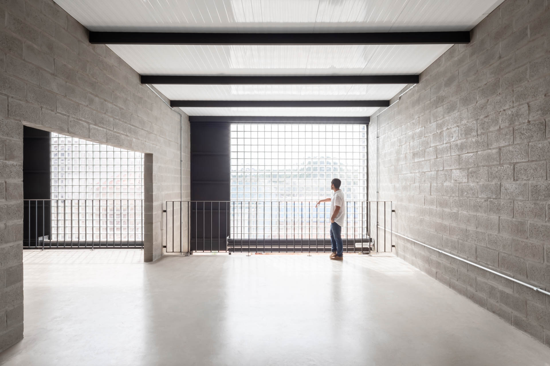 Um homem está parado em uma sala vazia olhando pela janela.