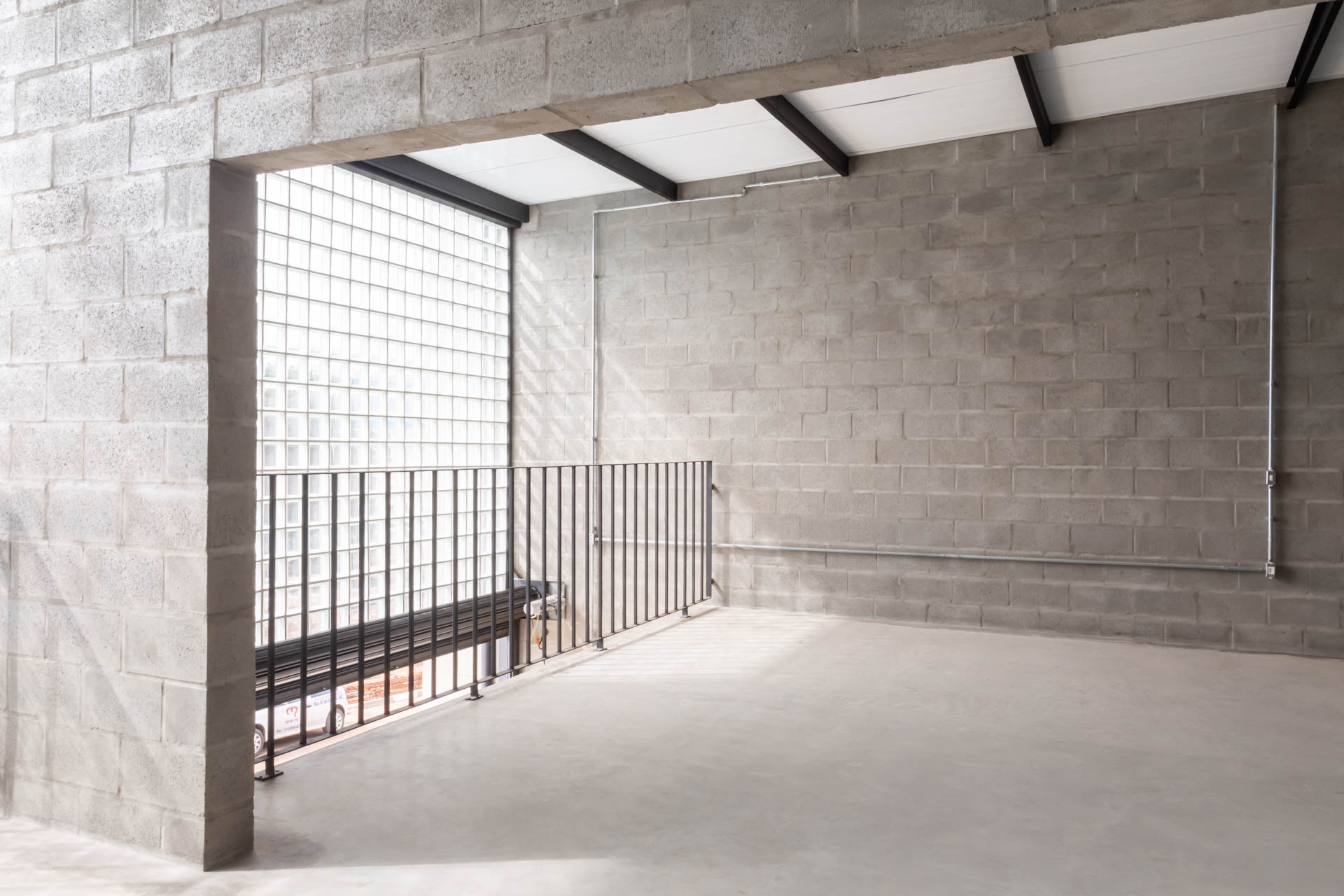Uma sala vazia com uma parede de tijolos e uma grade de metal.