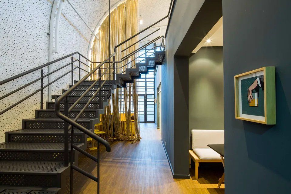 Um corredor com escadas e um quadro na parede.