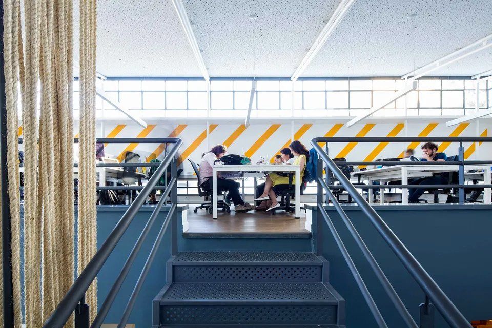 Um grupo de pessoas está sentado em mesas em um escritório