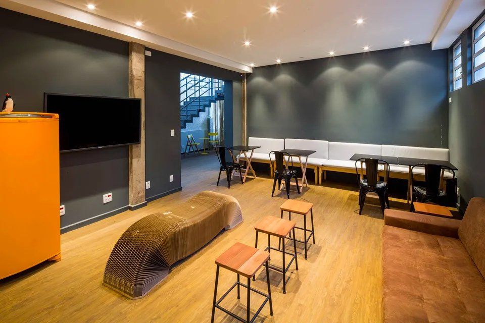 Uma sala de estar com mesas e cadeiras e uma TV de tela plana.