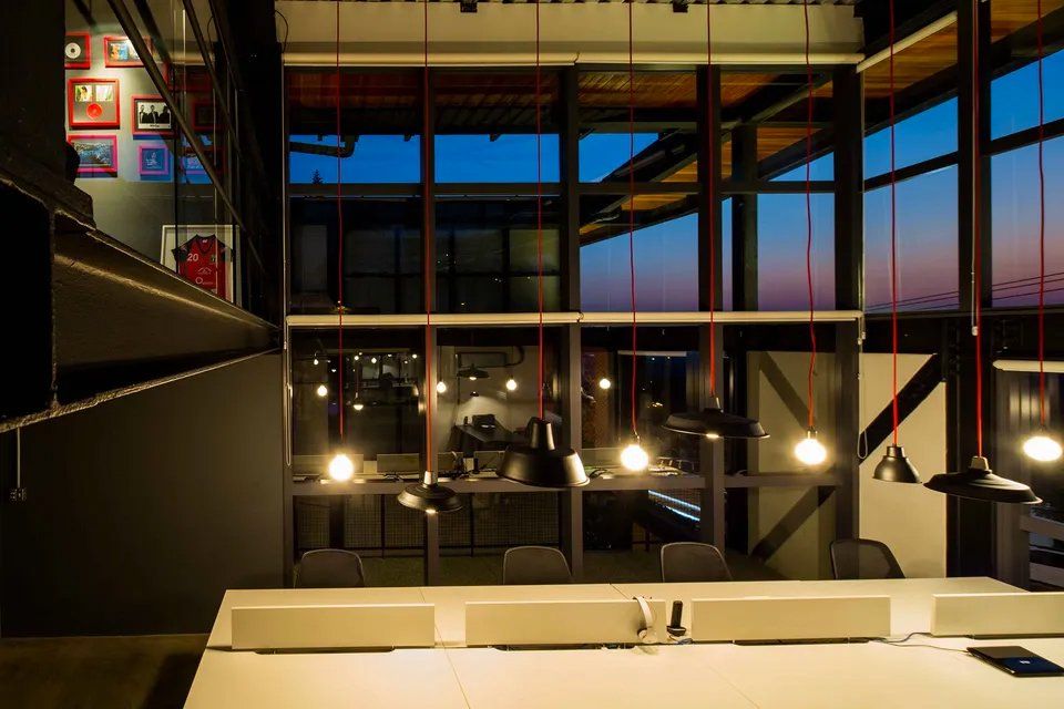 Uma sala com muitas janelas e uma mesa com um laptop