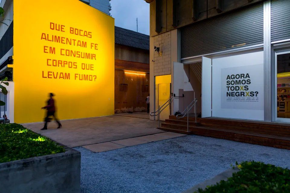 Um homem está andando na frente de um prédio com uma placa