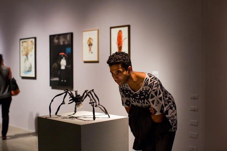 Um homem está olhando para a escultura de uma aranha em um museu.