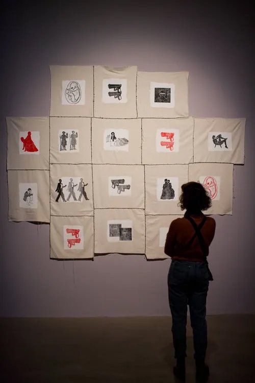 Uma mulher está parada em frente a uma parede com muitas fotos.