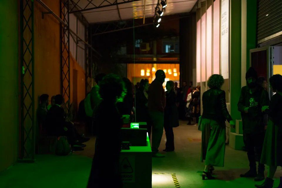 Um grupo de pessoas está em uma sala escura com luzes verdes.