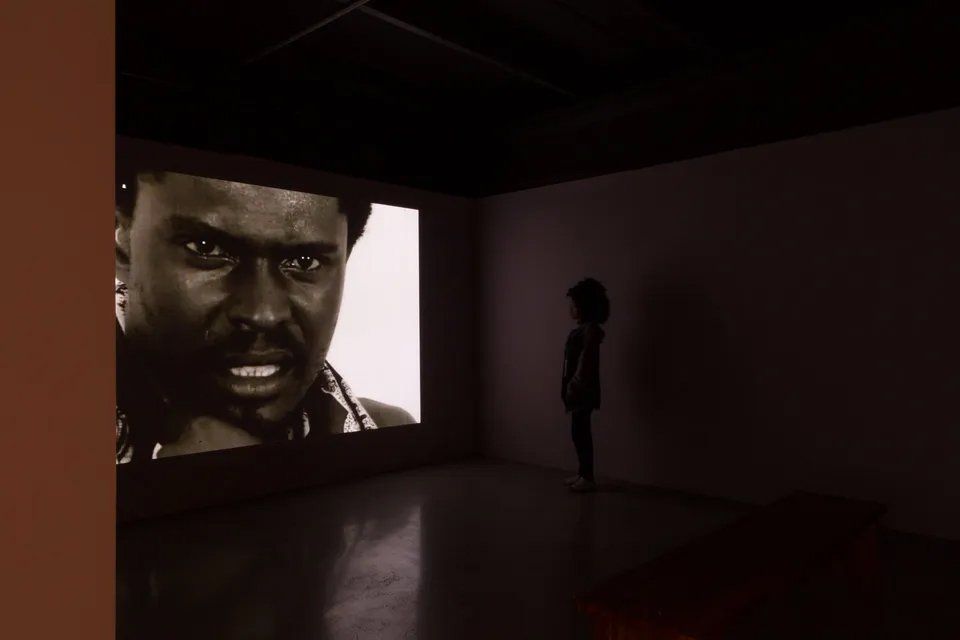 Uma foto em preto e branco do rosto de um homem é projetada na parede.