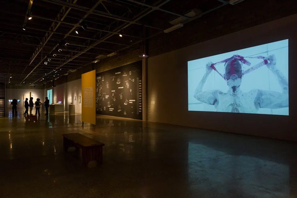 Um grupo de pessoas está em uma sala escura em frente a uma grande tela.