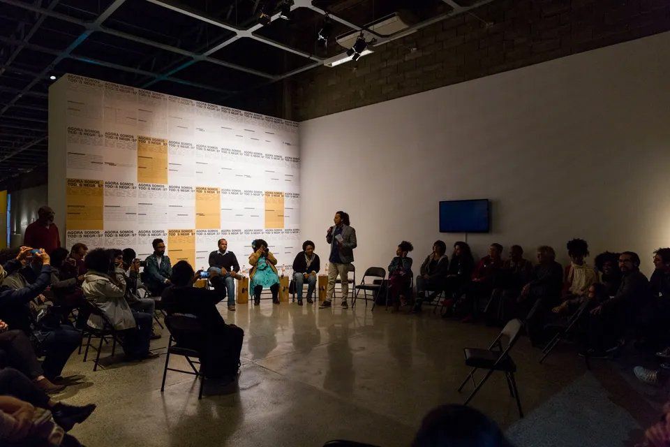 Um grupo de pessoas está sentado em círculo em uma sala escura.