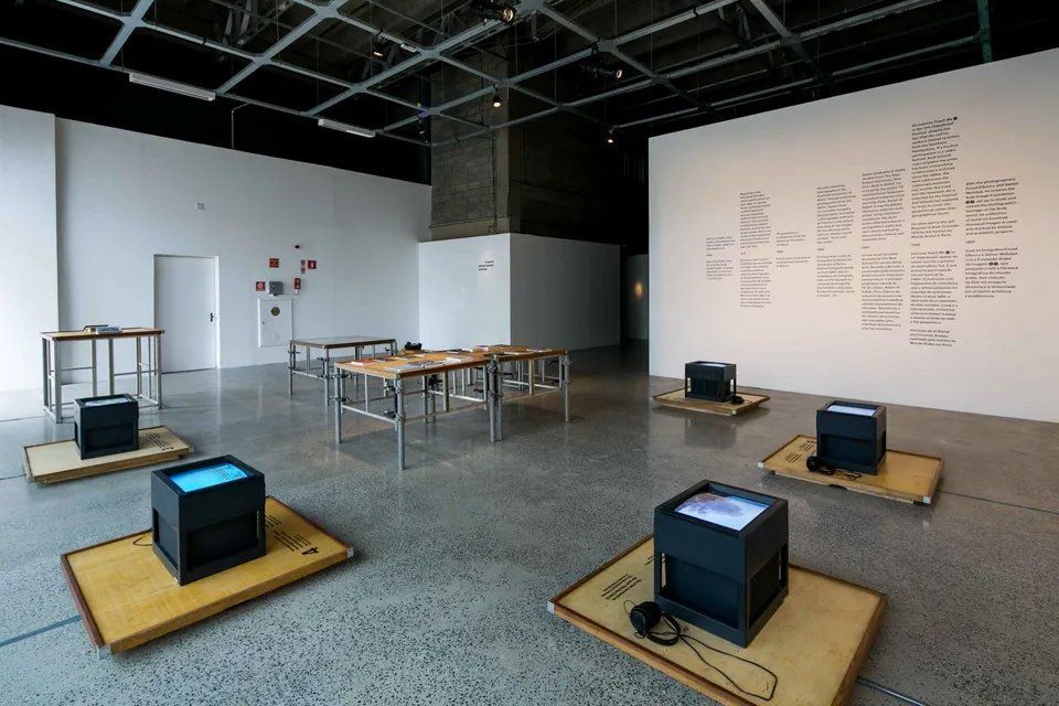 Uma sala grande com muitas mesas e cubos no chão.