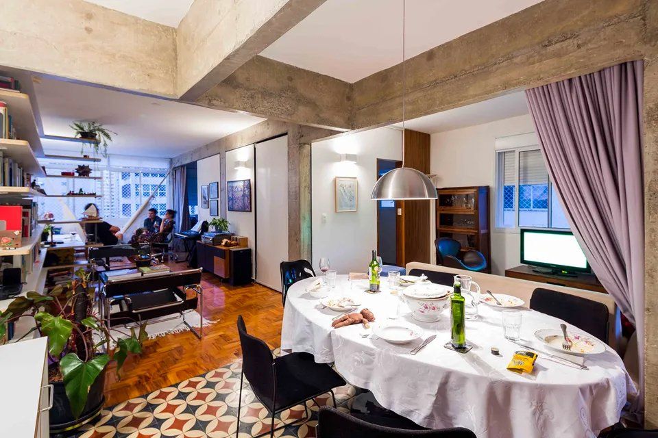 Uma mesa de jantar com toalha branca e cadeiras em uma sala de estar.