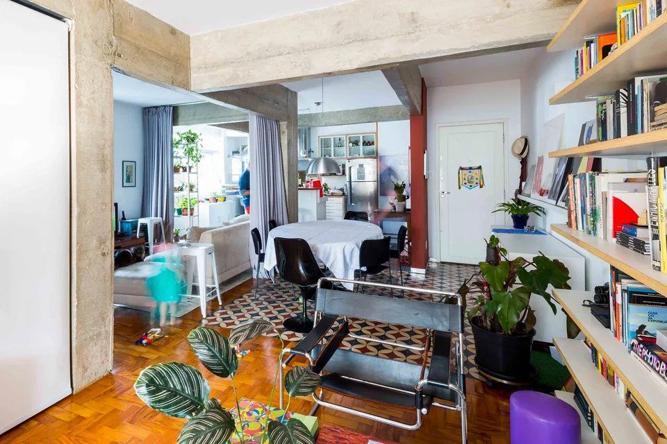 Uma sala de estar com mesa e cadeiras e uma estante cheia de livros.