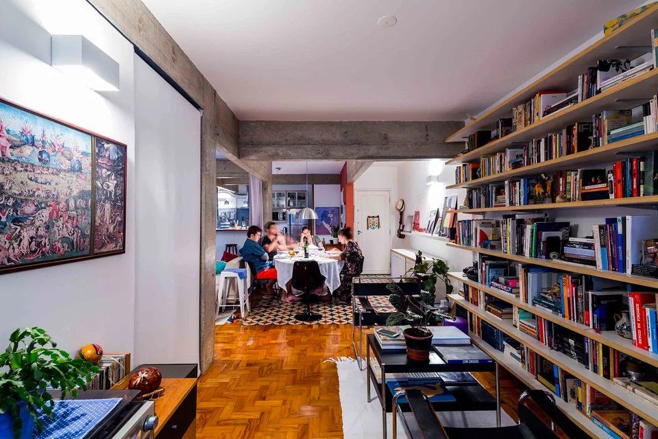 Uma família está sentada à mesa de uma sala cercada por estantes de livros.